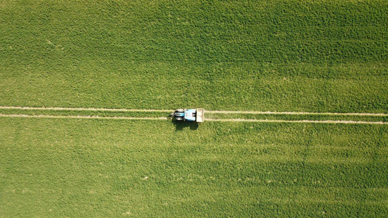 Aerial view of a tractor crossing a green field
